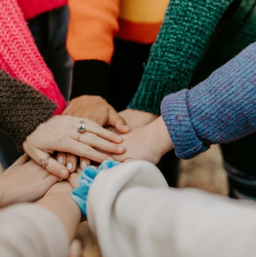 person in red sweater holding babys hand